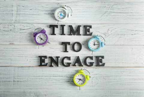 Clocks and phrase TIME TO ENGAGE on wooden background